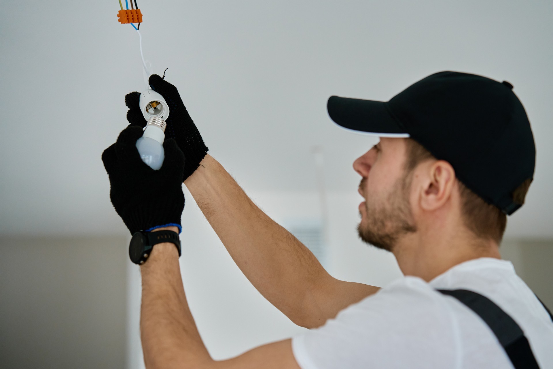 Electrician installing light bulb in new apartment during renovation